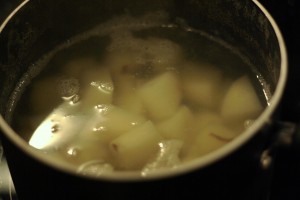 Cover potatoes with cold water in a saucepot.  Bring water to boil.  Add the smashed garlic cloves.  Boil potatoes until fork tender.  Stir pot occasionally.  This should take about 15-20 minutes.  Be sure to keep watch, because the water tends to boil over if the heat is too high.  Lower the heat if you think the pot is going to boil over.