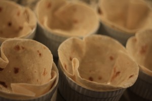 Spray oven safe ramekin with baking spray.  Line each ramekin with 8 inch tortilla.  Lightly spray each tortilla with baking spray.  Bake in the oven on 350 degrees Fahrenheit for about 10 minutes, or until the tortillas are crispy. 