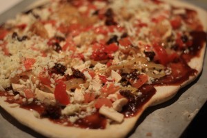 Next, top pizza with the onions, chicken, roasted red peppers, and sun dried tomatoes.  Sprinkle on the dried basil all over. 