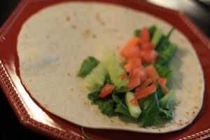 Using an 8 inch flour tortilla, layer in lettuce, a few slices of carrots, a few slices of celery, and chopped tomato.