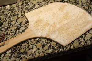 I use a board to transfer the pizza crust to the stone.  Flour the board all over, then sprinkle some breadcrumbs or cornmeal on the board.  Lay the crust on the board.