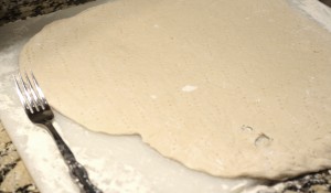 Roll out pizza dough to 14-16 inches (or to fit your pizza stone or pan).  Prick the dough all over with a fork.  This will help to keep the crust from puffing up during the par bake.