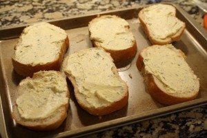 Lay the slices of bread onto a baking sheet. (You can spray the baking sheet with non-stick spray, but it isn’t necessary.)  Spread the butter mixture onto each slice of bread.  I was able to get about ½-1 tbsp of the butter onto each slice.  (Use as much or as little as you like, you can always store the rest of the mixture in the fridge, covered,, within a 2 or 3 days.)