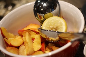 Place the sliced peaches into a large mixing bowl and sprinkle with the juice of ½ a lemon.  Toss to combine.