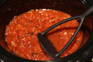 While the meat is cooking, prepare the other ingredients in the slow-cooker.  Pour the diced, fire roasted tomatoes into a slow-cooker.  Give them a little mash with a potato masher.