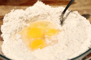 Put flour into a mixing bowl.  Create a little well in the middle.  Add the yolks, egg, and water into the well.