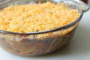 Top the chili casserole with the shredded cheddar cheese.